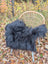 Black fluffy long wool icelandic sheepskin throw draped over a wicker chair showcasing natural wool icelandic texture