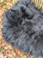 A plush dark gray long wool icelandic sheepskin throw blanket with soft voluminous texture for cozy use