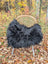 Black fluffy long wool icelandic sheepskin chair cover draped over wicker chair with metal legs