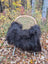 Black fluffy long wool icelandic sheepskin throw draped over woven wicker chair for cozy decor