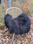 Black fluffy long wool icelandic sheepskin throw draped over woven rattan chair with light legs