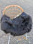Black long wool icelandic sheepskin chair cover draped over wicker chair with white metal legs
