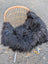 Black fluffy long wool icelandic sheepskin throw draped over wicker chair for cozy decor