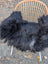 Black fluffy long wool icelandic sheepskin throw draped over wicker chair for cozy natural decor
