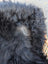 A fluffy black dog with gray patch on its back lying on a long wool natural black icelandic sheepskin rug