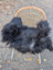 Black fluffy long wool icelandic sheepskin chair cover draped over woven wicker chair with metal legs