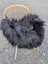 Black fluffy wool icelandic sheepskin long wool throw draped over a wicker chair for cozy decor