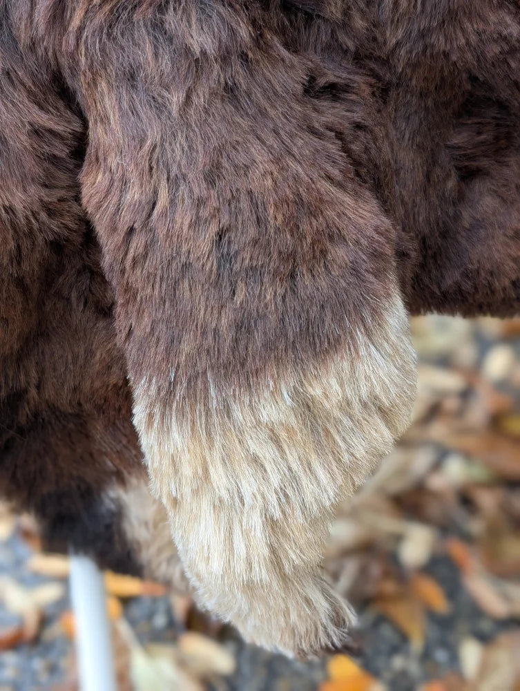 A plush dark brown and cream-colored furry paw made from soft wool icelandic sheepskin short wool for comfort