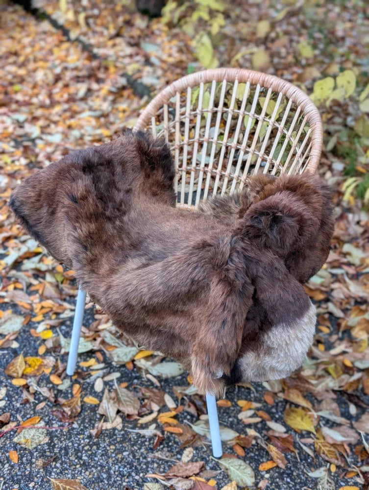 Brown icelandic sheepskin wool rug draped over wicker chair showcasing soft wool icelandic texture and warmth