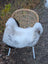 A cozy white and gray icelandic sheepskin rug with long wool and dark edges draped over a wicker chair
