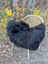 Black fluffy long wool icelandic sheepskin throw draped over woven wicker chair with white metal legs