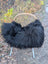 Black fluffy long wool icelandic sheepskin throw draped over woven wicker chair with white metal legs