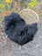 Black fluffy long wool icelandic sheepskin draped over woven wicker chair perfect for cozy decor