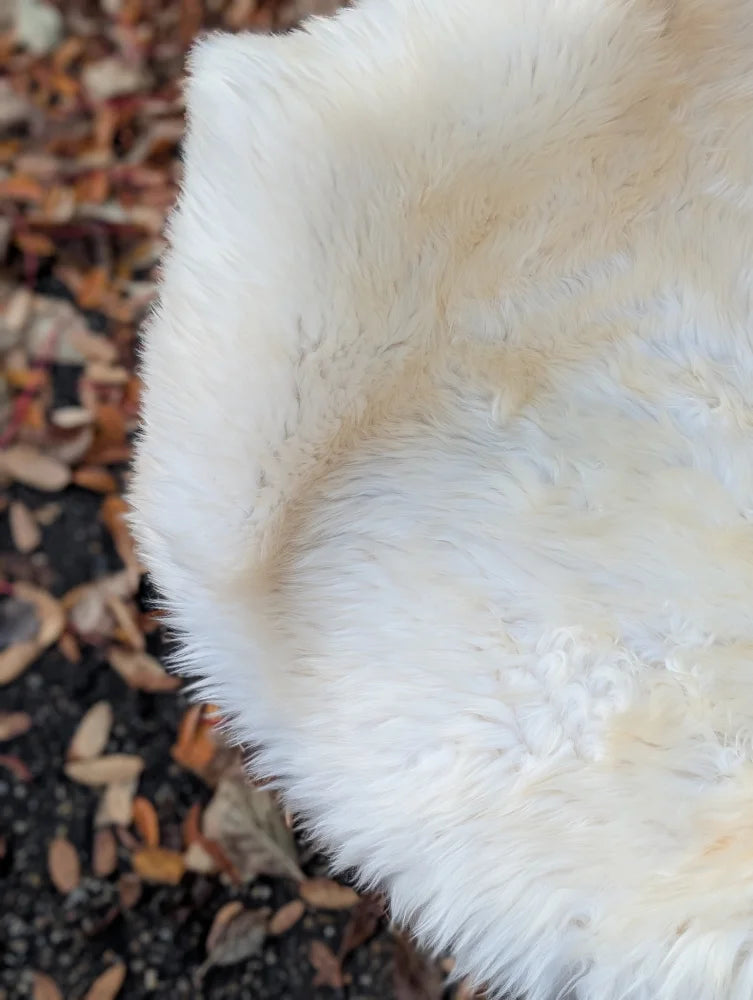 A soft creamy white faux fur rug with plush dense texture and uneven edges ice64 british isles sheepskin