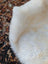 A plush off-white very soft british isles sheepskin rug with dense faux fur texture and slightly uneven edges