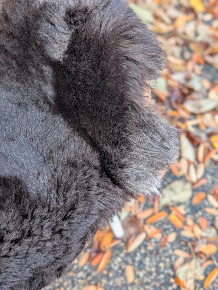 A plush dark gray wool icelandic sheepskin coat sleeve with soft dense texture and slightly frayed dark edges