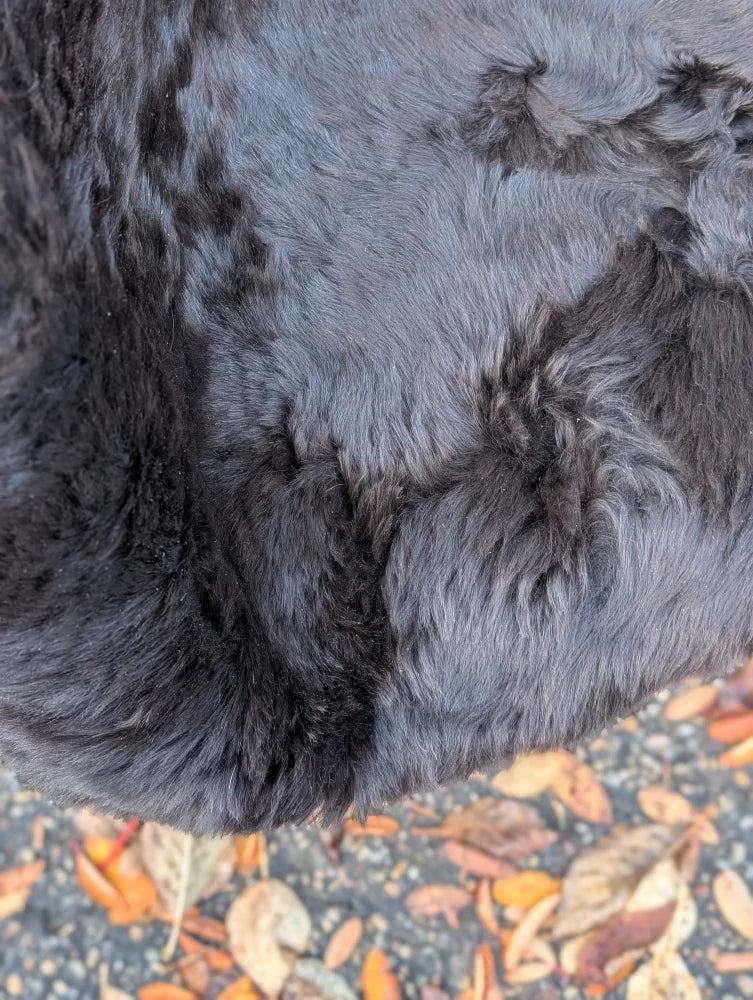 A plush dark gray wool icelandic sheepskin coat with soft textured surface and dark edges slightly matted areas