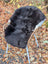 A cozy black and white wool icelandic sheepskin chair with dark edges, woven wicker frame, and light blue metal legs