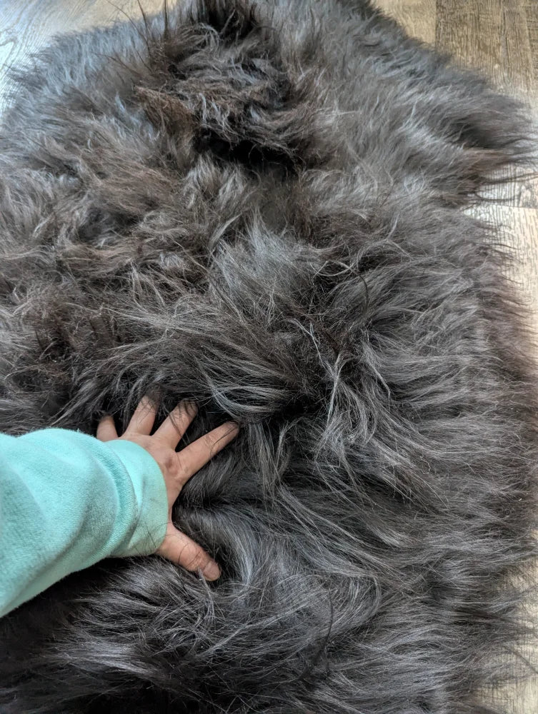 A plush dark gray long wool icelandic sheepskin rug with natural blacky soft dense fibers and luxurious texture