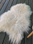 A plush off-white long wool icelandic sheepskin rug with curly fibers on a dark wooden deck