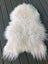 A plush off-white icelandic sheepskin rug with long curly wool and a natural irregular shape perfect for cozy decor