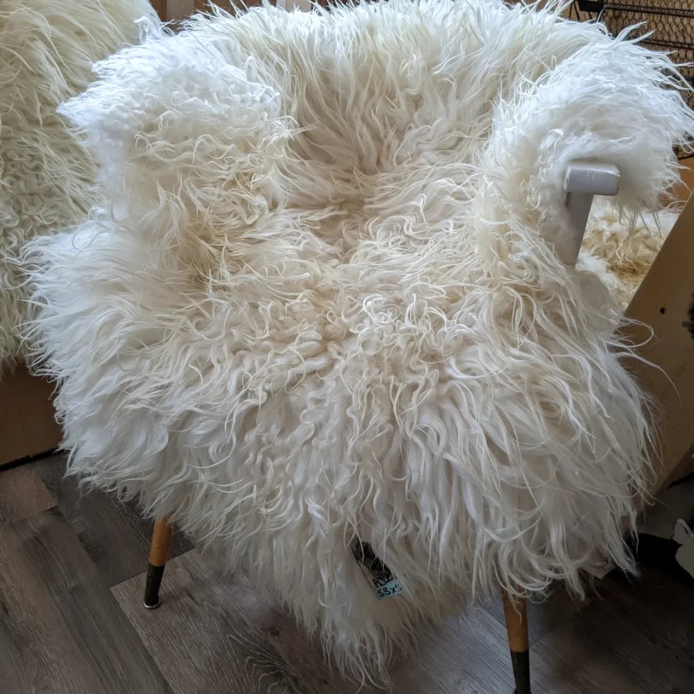 A plush off-white icelandic sheepskins chair with long wool icelandic curly fur and wooden legs