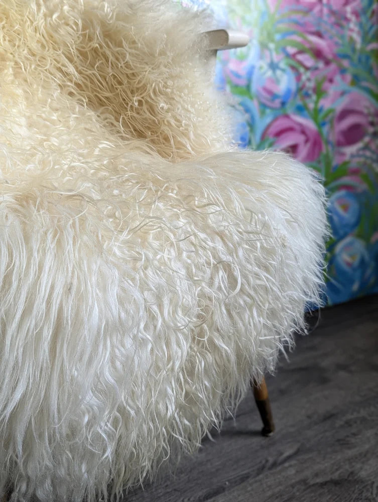 Cream-colored ultra-soft curly sheepskin chair with long wool icelandic natural texture and wooden legs