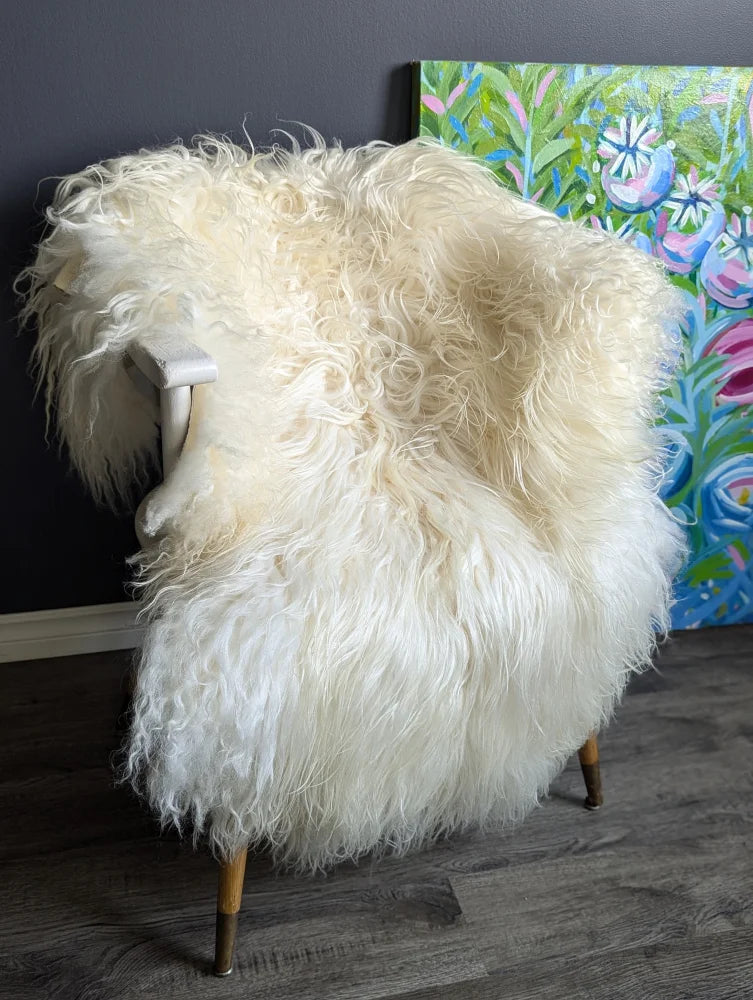 Cream-colored thick long wool icelandic sheepskin throw draped over chair natural textured cozy look