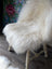 A natural white icelandic sheepskin with long wool draped over a vintage wooden chair for cozy seating
