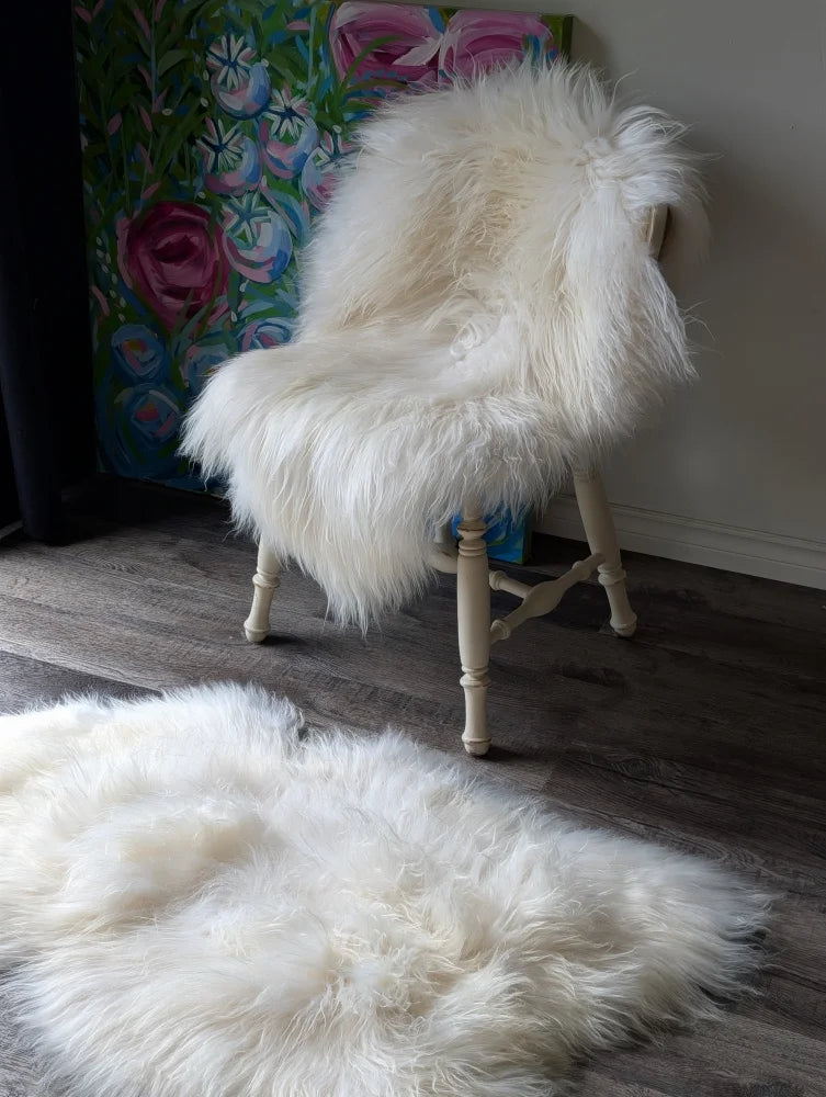 A natural white icelandic sheepskin with long wool draped over a vintage wooden chair for cozy seating