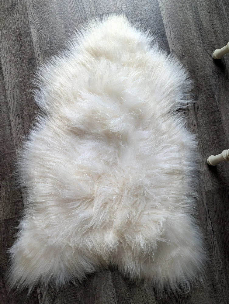 A plush natural white icelandic sheepskin rug with long wool and a soft irregular shape perfect for cozy decor