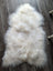 A plush natural white icelandic sheepskin rug with long wool and a soft irregular shape perfect for cozy decor