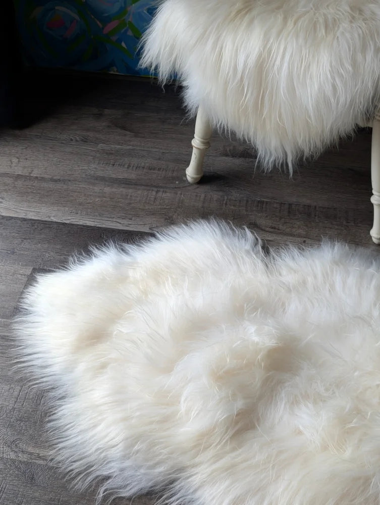 Natural white icelandic sheepskin rug with long wool fibers on dark wood floor perfect for cozy decor