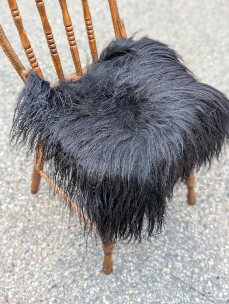 Black long-haired faux fur chair pad with plush shaggy texture in natural black icelandic sheepskin style