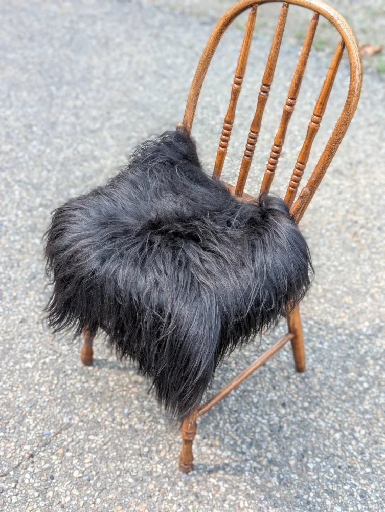 Black fluffy icelandic sheepskin chair square with plush long-haired natural black texture for cozy seating