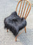 Black fluffy icelandic sheepskin chair square with plush long-haired natural black texture for cozy seating