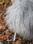Back view of a massive icelandic sheepskin gray plush chair with long wool faux fur and wicker frame with white legs