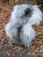 Fluffy gray and white natural grey icelandic sheepskin chair cover with long wool draped over a wicker chair