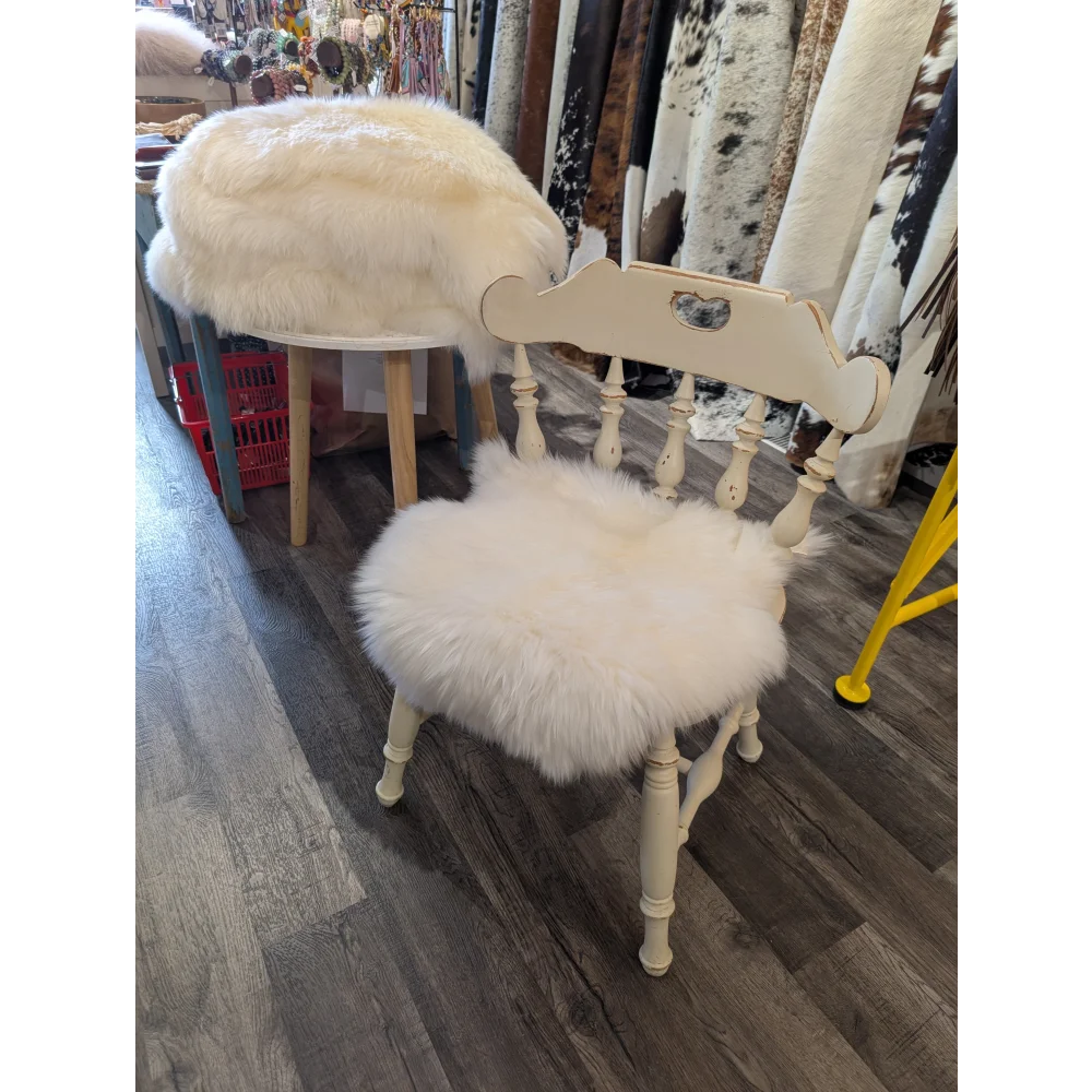 Cream-colored wooden chair with fluffy white merino sheepskin chair pads on seat and backrest for extra comfort