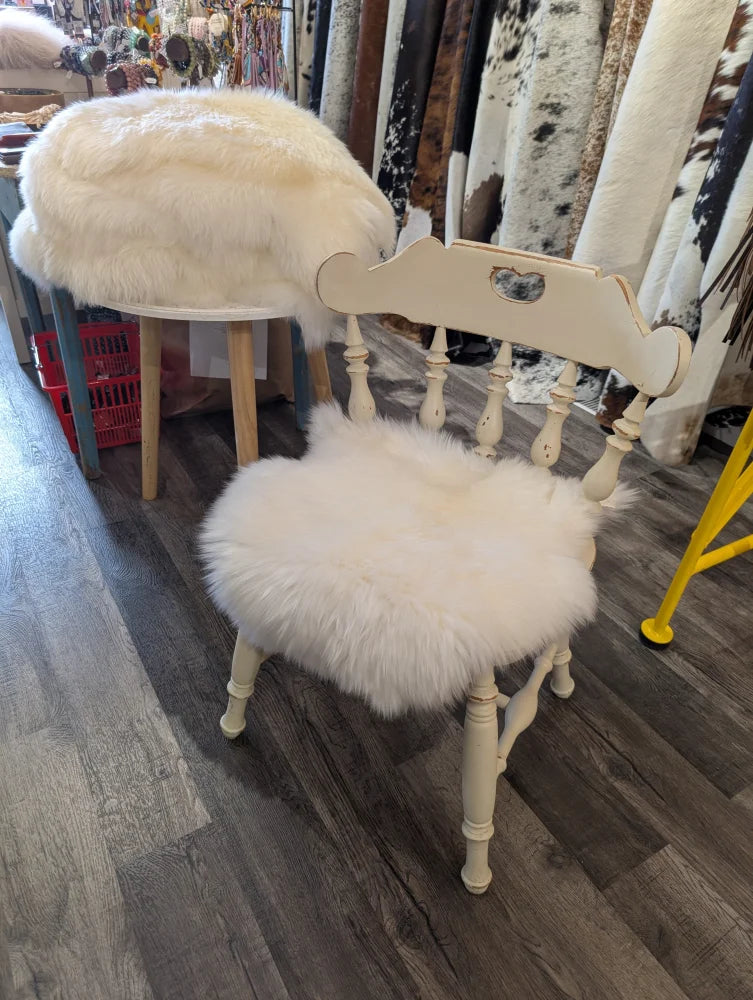 Cream-colored wooden chair with fluffy white merino sheepskin chair pads on seat and backrest for extra comfort