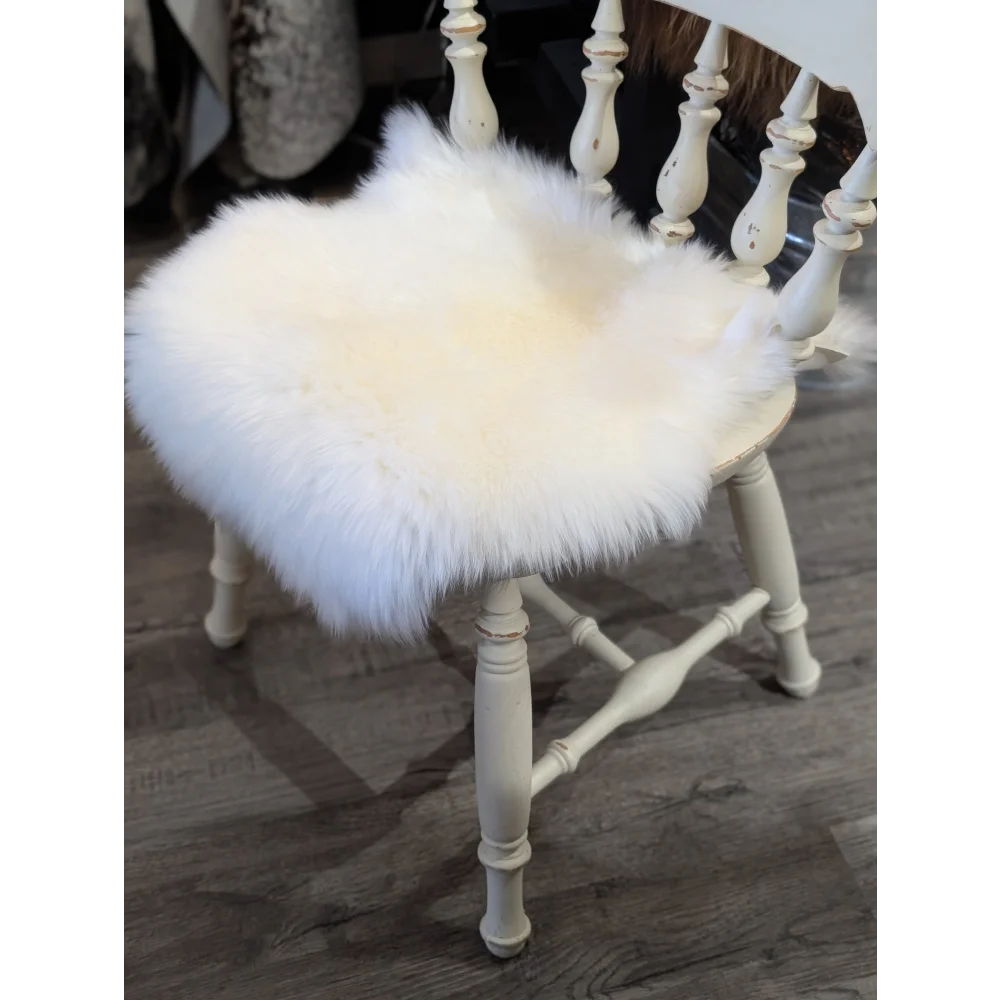 White fluffy merino sheepskin chair pad resting on a distressed white wooden chair for cozy seating