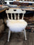 A white wooden chair with a heart cutout featuring a fluffy off-white merino sheepskin chair pad seat cushion