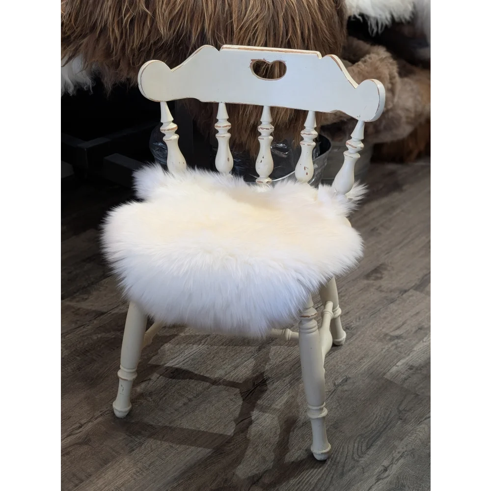 White distressed wooden chair with a fluffy white merino sheepskin chair pad for cozy seating comfort
