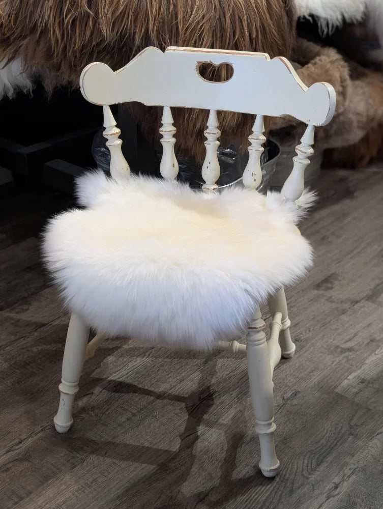 White distressed wooden chair with a fluffy white merino sheepskin chair pad for cozy seating comfort