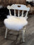 White distressed wooden chair with a fluffy white merino sheepskin chair pad for cozy seating comfort