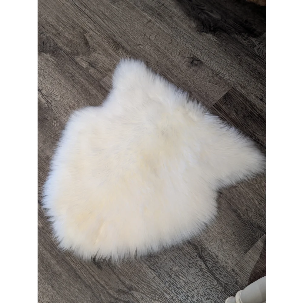 A large off-white merino sheepskin chair pad with a soft fluffy texture on a dark wood floor perfect as chair pads