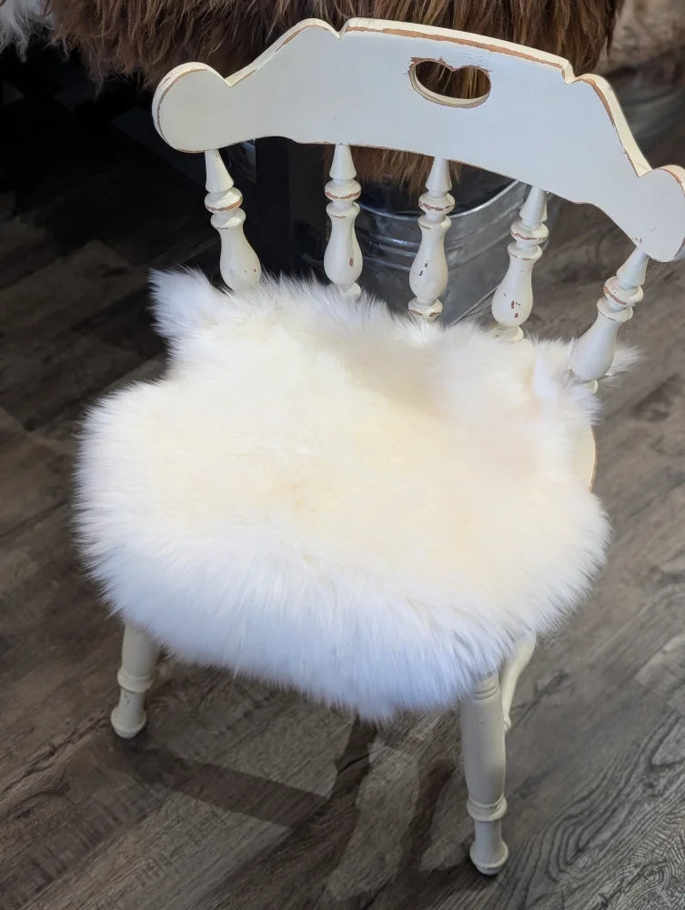 White distressed wooden chair with fluffy white merino sheepskin chair pad for cozy seating comfort