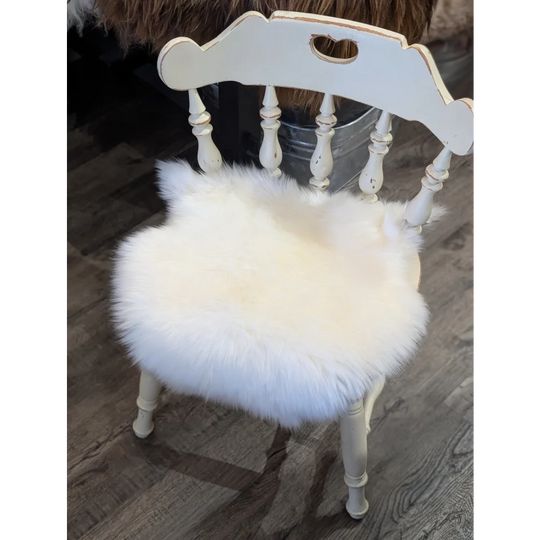 White distressed wooden chair with fluffy white merino sheepskin chair pad for cozy seating comfort