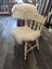 Cream-colored wooden chair with fluffy white merino sheepskin chair pads on seat and backrest for extra comfort