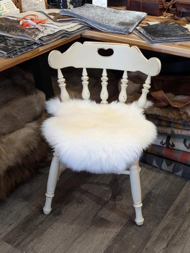 White painted wooden chair with a fluffy white merino sheepskin chair pad for cozy seating comfort